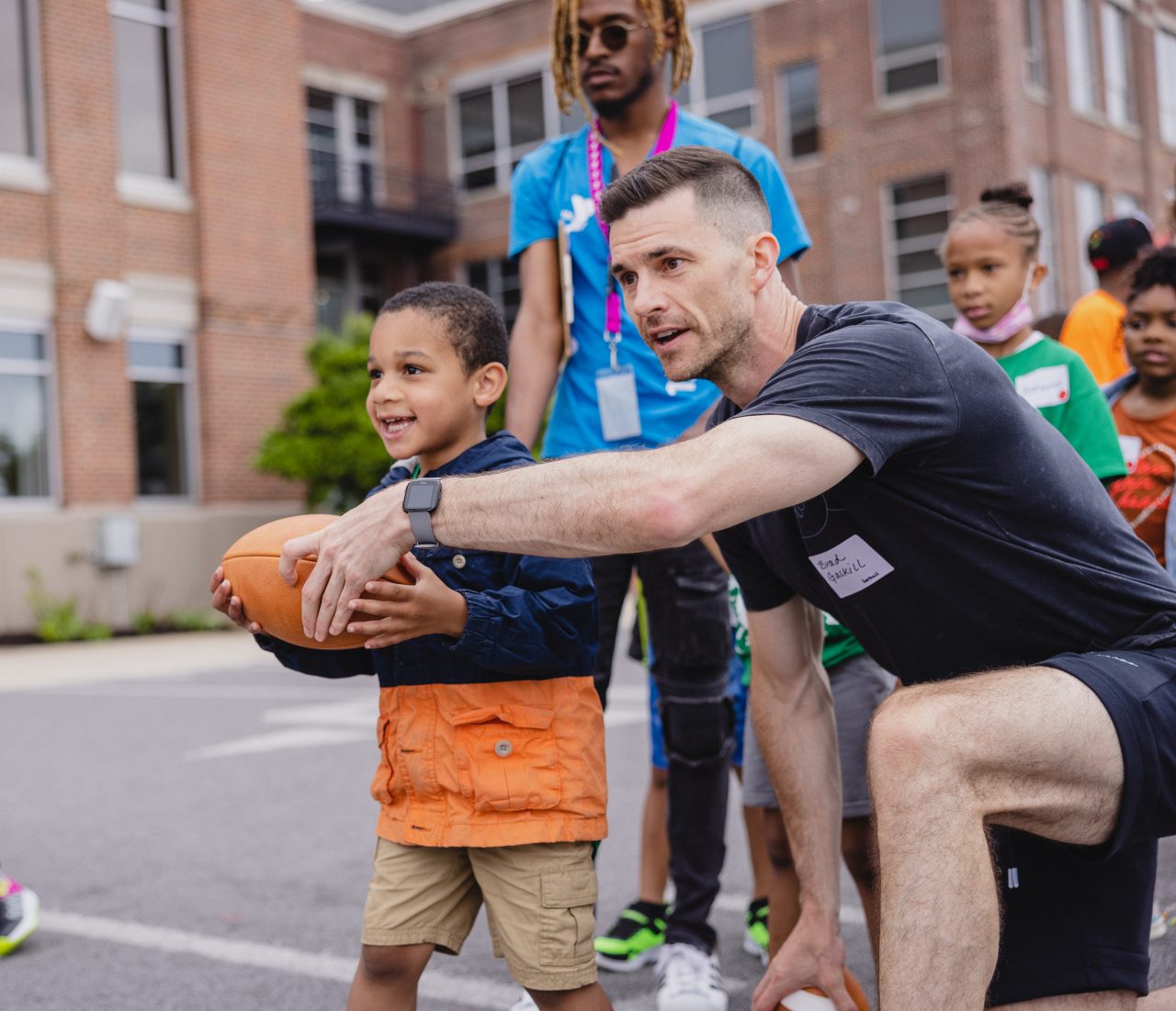 25X25 UA teammate Volunteer on field with children